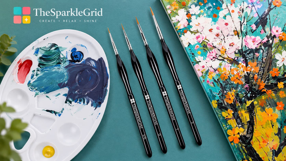 Four black paintbrushes from The Sparkle Grid are arranged on a teal surface next to a white paint palette with mixed blue, green, red, and yellow paint, and a colorful painted canvas showing floral branches.