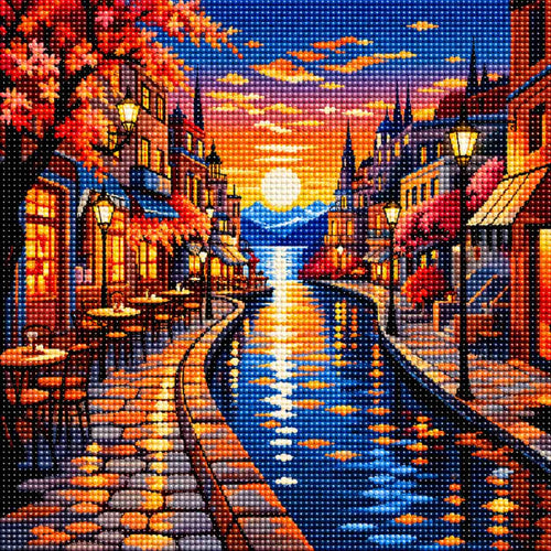 TheSparkleGrid diamond painting artwork featuring a colourful sunset canal town with glowing cafés, historic buildings, street lamps, distant mountains and sparkling water reflections.