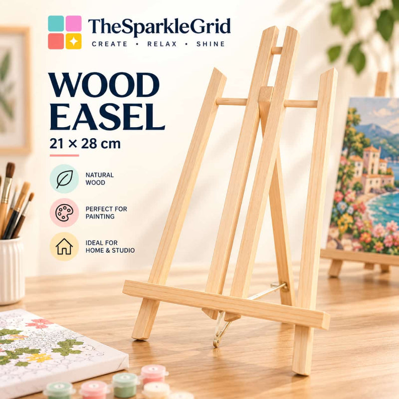 A light natural wood tabletop easel shown on a wooden surface in a styled studio setup. The product is branded TheSparkleGrid, with text reading 'WOOD EASEL 21 x 28 cm' and feature callouts including natural wood, painting-friendly, and ideal for home and studio.